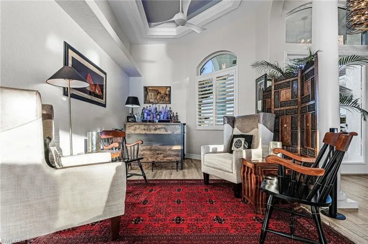 Living area with wood finished floors, ceiling fan, and a tray ceiling