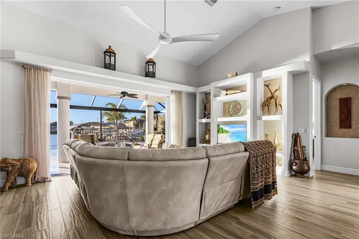 Living area featuring a sunroom, wood finished floors, lofted ceiling, and ceiling fan