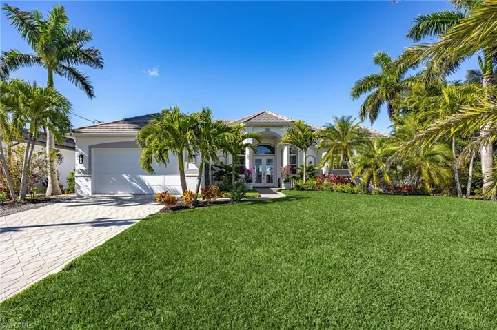 View of front of house with french doors, a front lawn, decorative driveway, an attached garage, and stucco siding