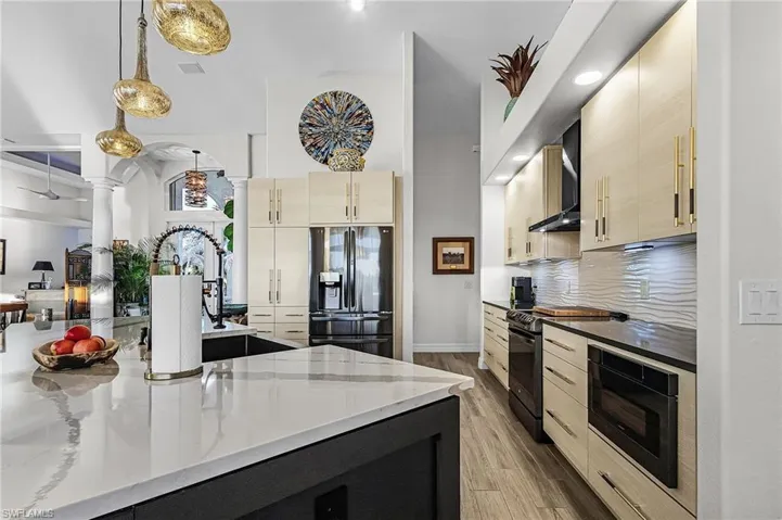 Kitchen featuring light brown cabinetry, dark stone counters, black appliances, modern cabinets, and tasteful backsplash