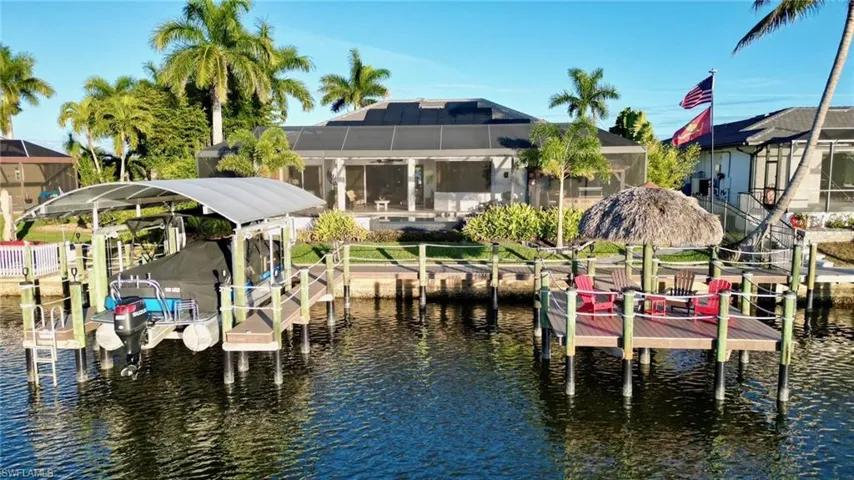Dock featuring boat lift, a water view, glass enclosure, and a sunroom
