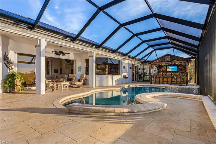 View of swimming pool featuring a lanai, a sunroom, a patio area, and a pool with connected hot tub