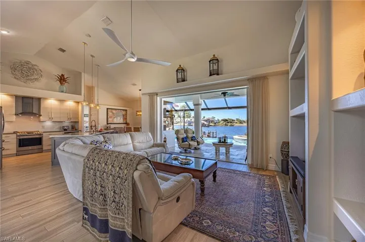 Living area featuring a water view, ceiling fan, light wood finished floors, and high vaulted ceiling