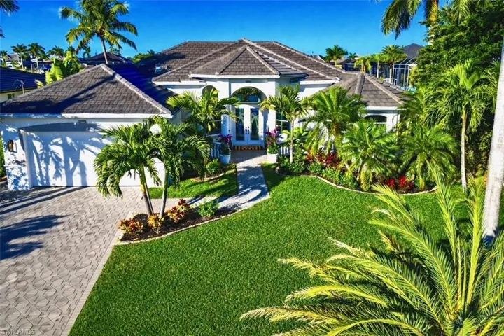 Mediterranean / spanish house with a tile roof, a front yard, stucco siding, an attached garage, and decorative driveway
