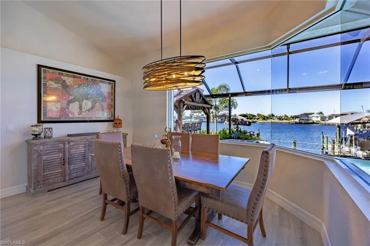 Dining space featuring light wood finished floors, a water view, vaulted ceiling, and a chandelier