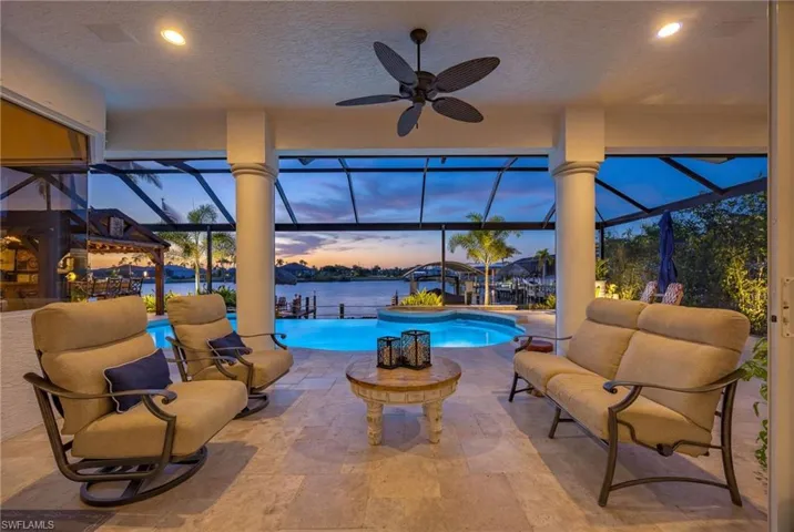 Outdoor pool featuring a sunroom, a lanai, a water view, and a patio