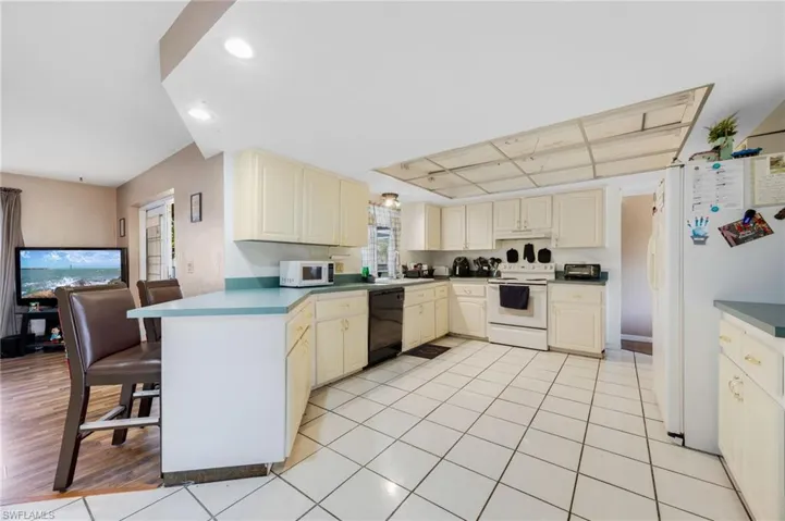 Kitchen featuring cream cabinets, light tile patterned flooring, and white appliances