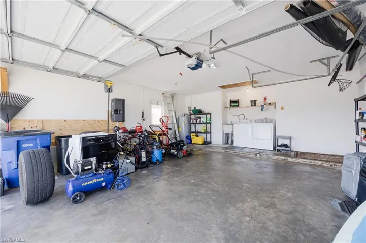 Garage featuring separate washer and dryer, water heater, and a garage door opener