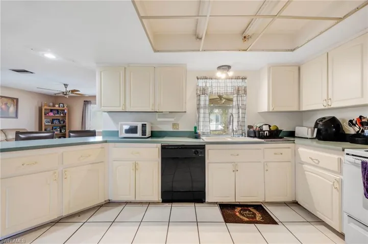 Kitchen featuring kitchen peninsula, white appliances, ceiling fan, sink, and light tile patterned floors