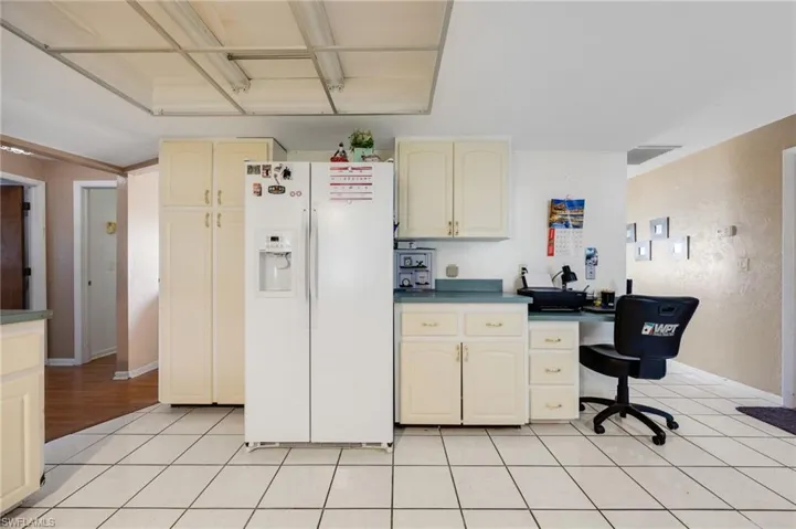 Kitchen featuring cream cabinetry, white fridge with ice dispenser, and light tile patterned floors