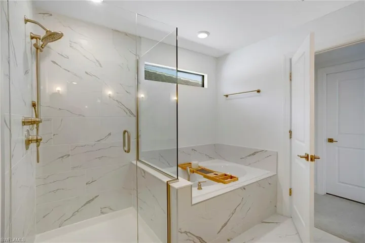 Full bathroom featuring marble finish floor, a marble finish shower, and a bath