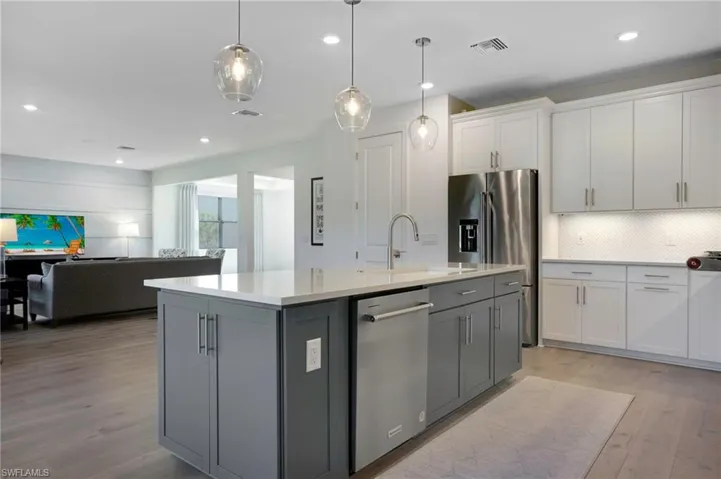 Kitchen featuring visible vents, light wood-style flooring, appliances with stainless steel finishes, light countertops, and backsplash