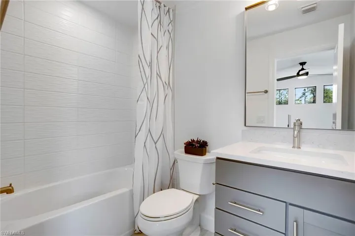 Bathroom featuring visible vents, toilet, a ceiling fan, shower / bath combo, and vanity
