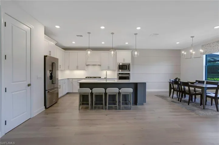 Kitchen featuring appliances with stainless steel finishes, light wood-style flooring, visible vents, and white cabinets