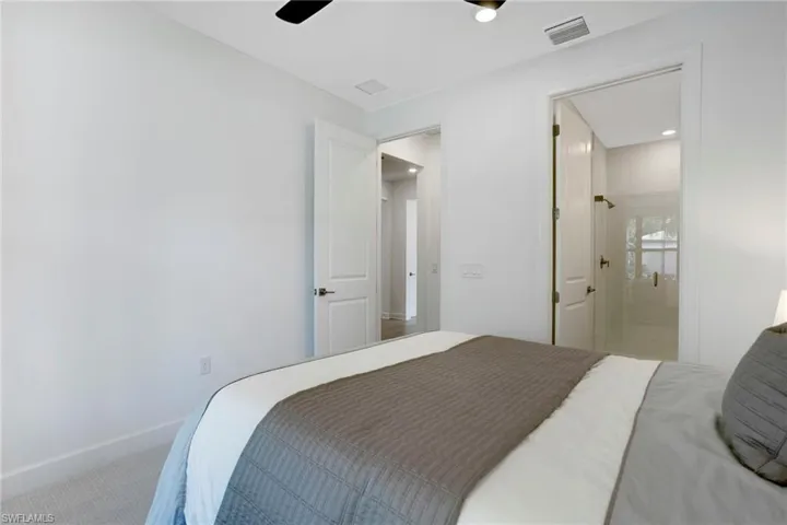 Carpeted first floor bedroom featuring ensuite bath, baseboards, and visible vents