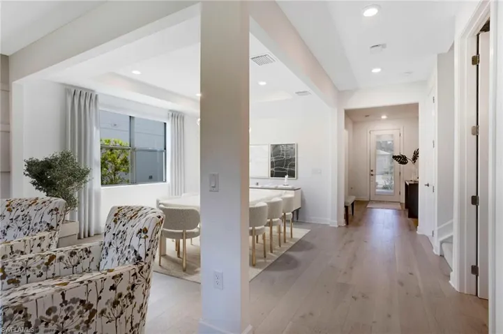 Hallway with a healthy amount of sunlight, light wood-style flooring, visible vents, and recessed lighting