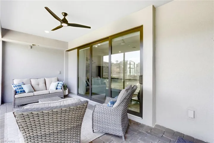 View Lanai featuring impact sliding glass doors, ceiling fan and outdoor lounge area. Ready for an outdoor kitchen