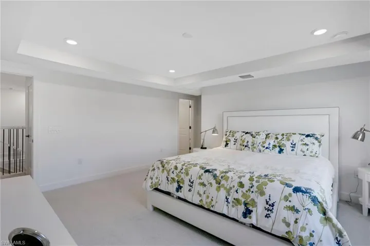 Bedroom featuring light carpet, visible vents, a raised ceiling, and recessed lighting