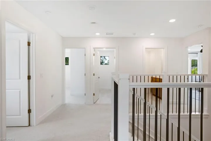 Hall with light carpet, a healthy amount of sunlight, an upstairs landing, and recessed lighting