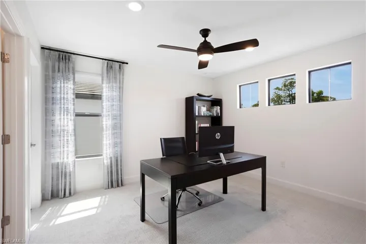 Office space with carpet floors, ceiling fan, and baseboards