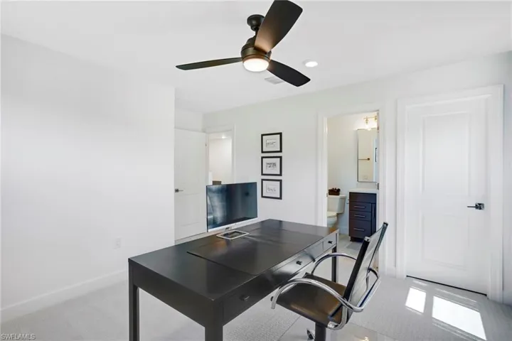 Office space featuring light carpet, baseboards, and a ceiling fan