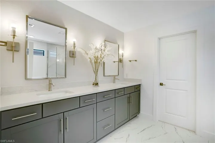 Full bathroom featuring double vanity, marble finish floor, and a sink