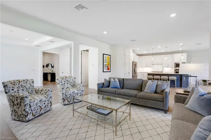 Living room with light wood finished floors, baseboards, visible vents, and recessed lighting