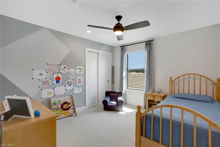 Bedroom with ceiling fan, a closet, and light colored carpet