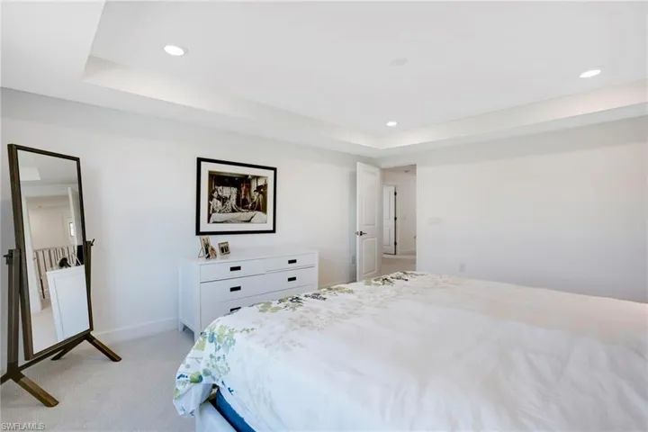 Bedroom featuring recessed lighting, baseboards, a raised ceiling, and light colored carpet