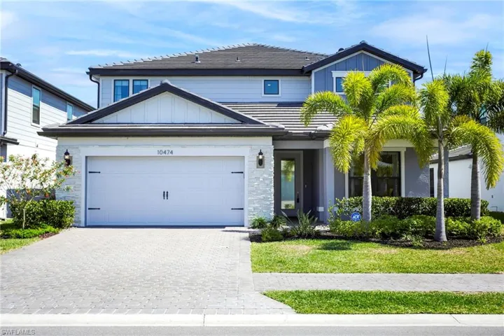 View of front of property with a garage, a tile roof, decorative driveway, and board and batten siding