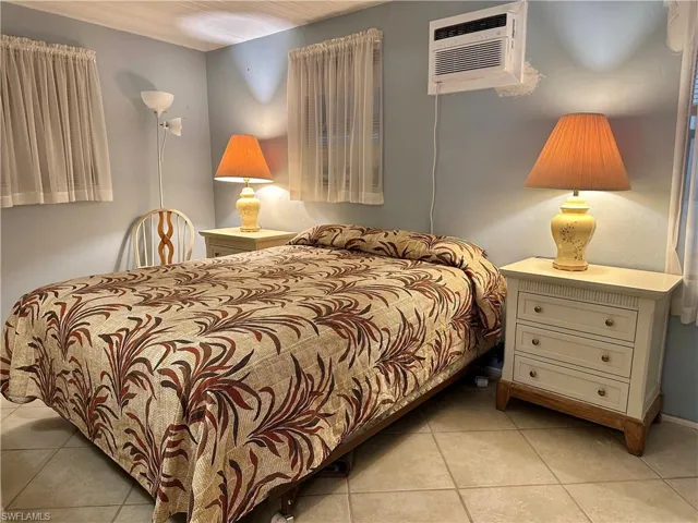 View of Large Primary Bedroom with light tile patterned floors and a wall mounted AC