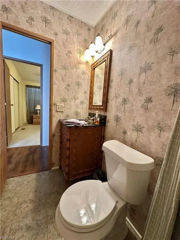 View of Updated/Renovated Second bath with vanity, a textured ceiling, tile patterned floors, and wallpapered walls and combo tub/shower.