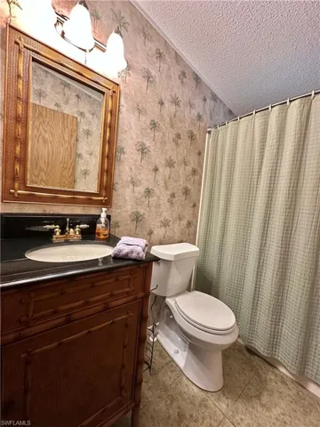 View of Updated/Renovated Second Updated Full bath with a textured ceiling, vanity, combo tub/shower, light tile patterned floors, and wallpapered walls