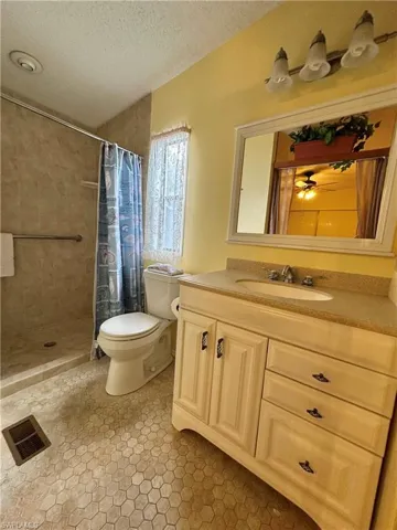 View of Primary full/renovated/upgraded bathroom with vanity, a textured ceiling, a shower stall, light tile patterned flooring, and ceiling fan