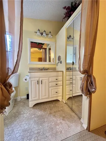 View of Primary bathroom entrance  featuring vanity and a textured ceiling and mirrow bifold shelving