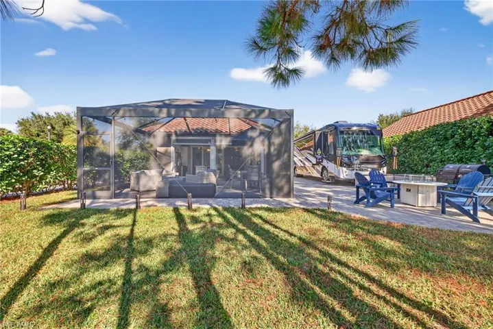 Rear view of house featuring a patio, a yard, a fire pit, and glass enclosure