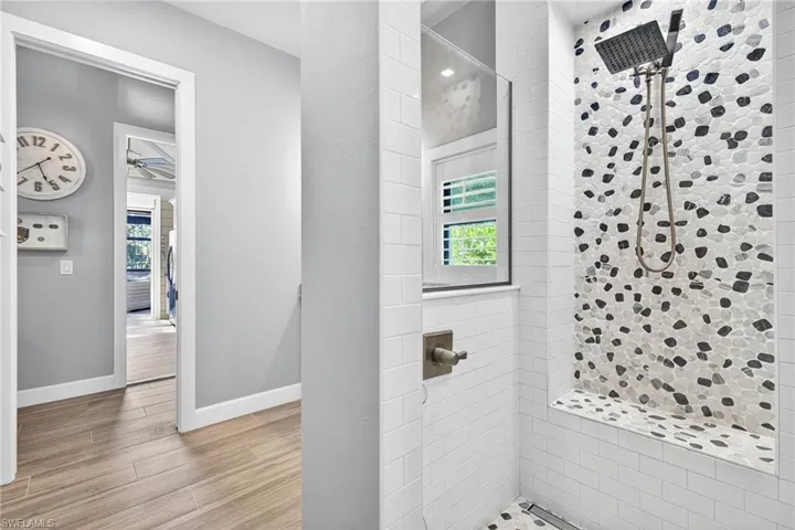 Full bathroom featuring a stall shower, light wood-type flooring, healthy amount of natural light, and a ceiling fan
