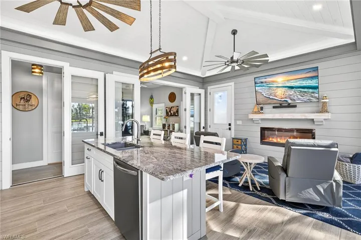 Kitchen with a breakfast bar, light stone counters, white cabinetry, a kitchen island with sink, and light wood-style flooring