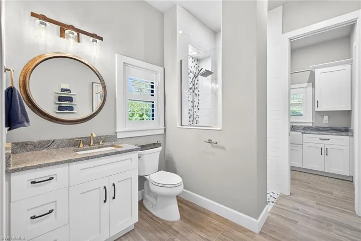 Bathroom featuring vanity, a walk in shower, and wood finish floors