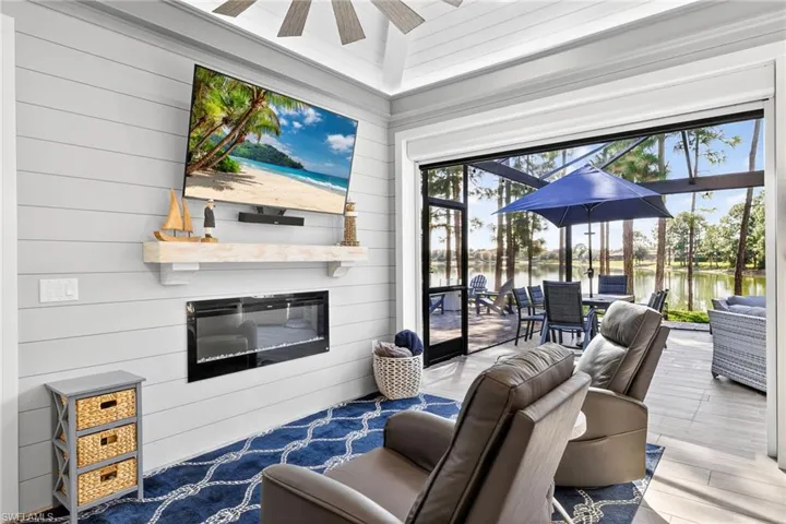 Living area with a sunroom, plenty of natural light, a glass covered fireplace, a ceiling fan, and wooden walls