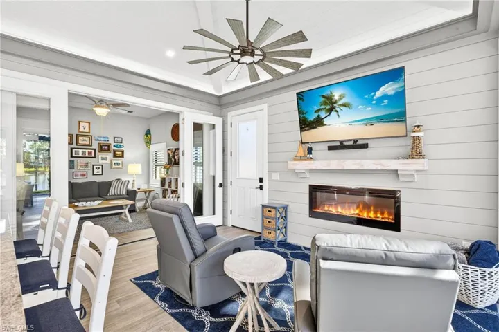 Living room with a glass covered fireplace, wood finished floors, ceiling fan, healthy amount of natural light, and recessed lighting