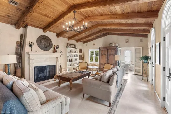 MAIN HOUSE - Living area featuring a vaulted wood-beamed ceiling, a stone fireplace, arched doorways, and built-in shelving