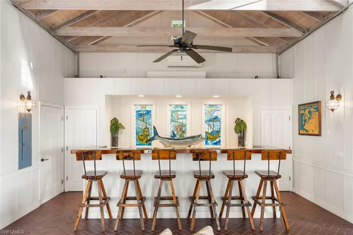 CLUBHOUSE - This spacious entertainment area features a substantial bar, exposed wood beam ceilings, and unique wall sconces providing ambient lighting