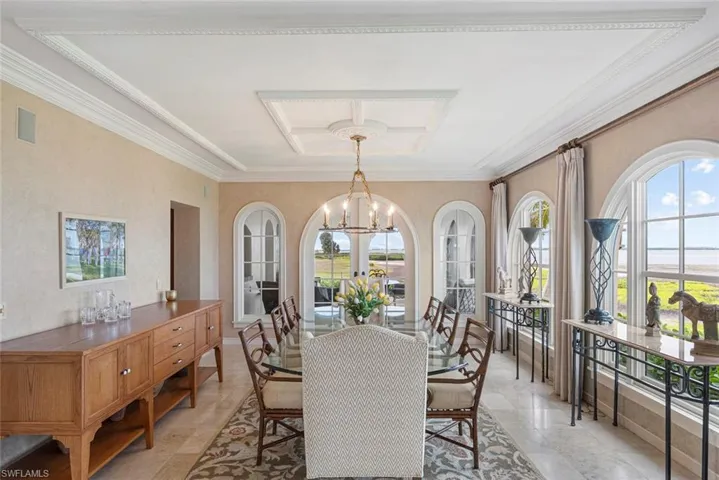 MAIN HOUSE -The property features a dining area with arched windows offering expansive views, an ornate chandelier, and detailed crown molding