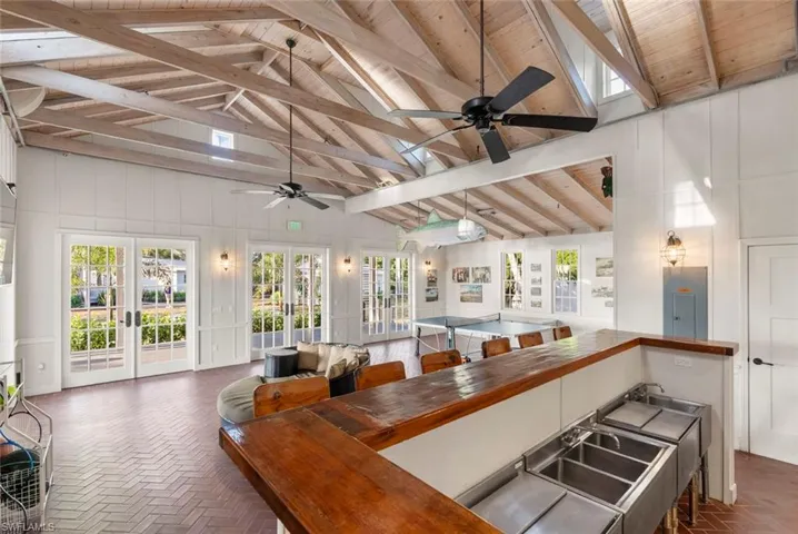CLUBHOUSE - Spacious entertainment area featuring an exposed beam vaulted ceiling, herringbone brick flooring, and French doors providing natural light