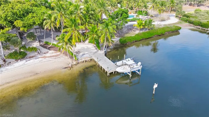 DOCK #2 The property features a private dock extending into calm waters, with a sandy beach shoreline