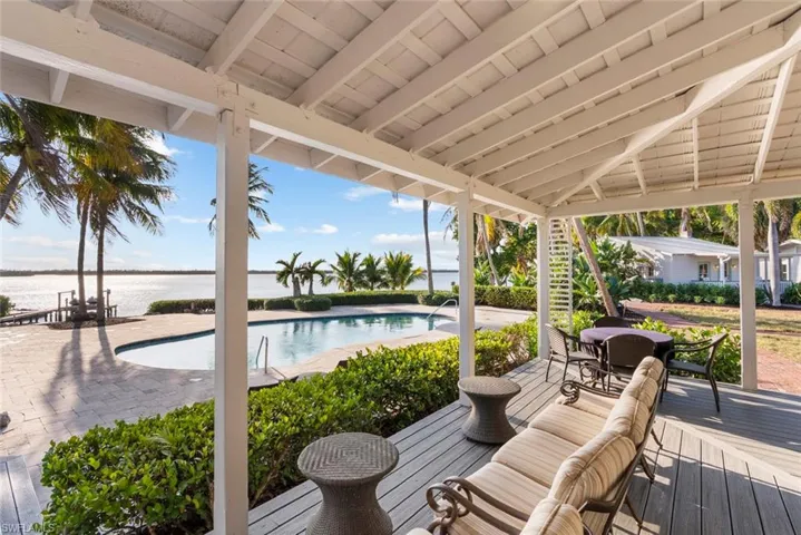 CLUBHOUSE - Expansive outdoor living area featuring a covered patio with a white slatted ceiling, a swimming pool, and views of the surrounding water