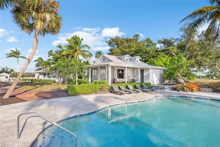POOL - The property features a pool with a tiled edge, a patio area with several lounge chairs, and a covered porch