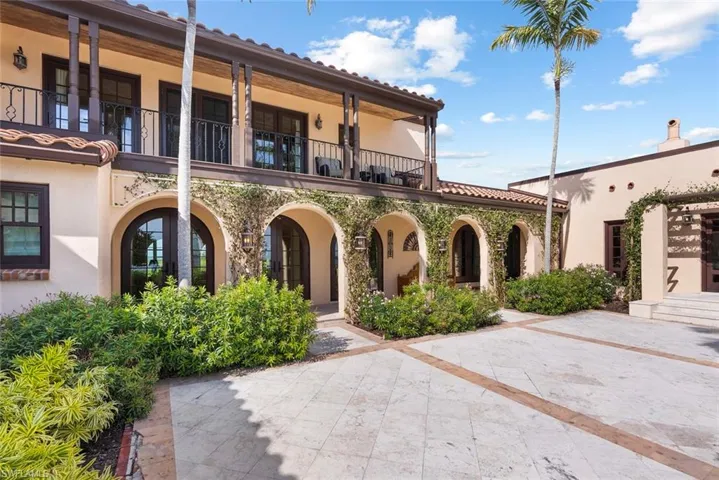 MAIN HOUSE - The property features an exterior with arched doorways and windows, tile roofing, and a second-story balcony with dark railings