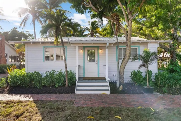 GUEST COTTAGE #2 - The property presents a charming facade with white siding and aqua trim, complemented by a metal roof